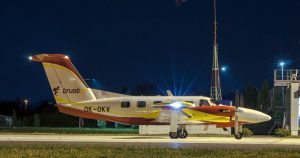 Side-view image of an ambulance aircraft with yellow and red linings on the tarmac during the night