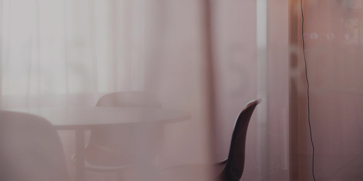 Image of a light pink conference room through pink curtains