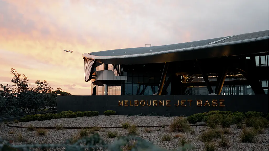 Image of the Melbourne Jet Base during dusk with an airplane flying over