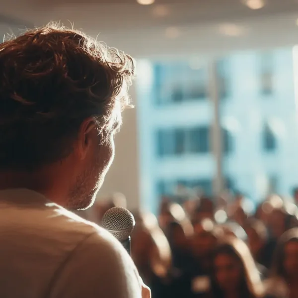 Cropped image of speaker presenting to a full audience at Node Talks conference in a sunlit room.
