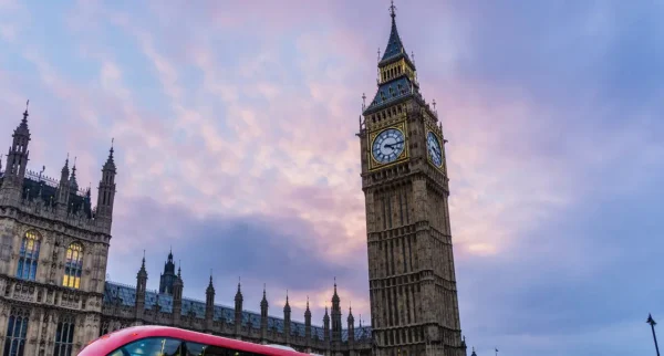 Big Ben clock tower in London at sunset with red double-decker bus