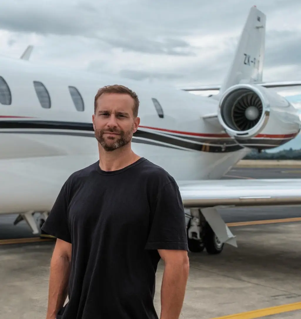 Image of Sam Sargent, founder of BLAK International standing by a jet