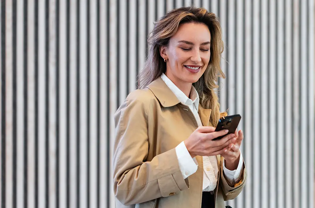 Image of a woman looking at her mobile phone, smiling.